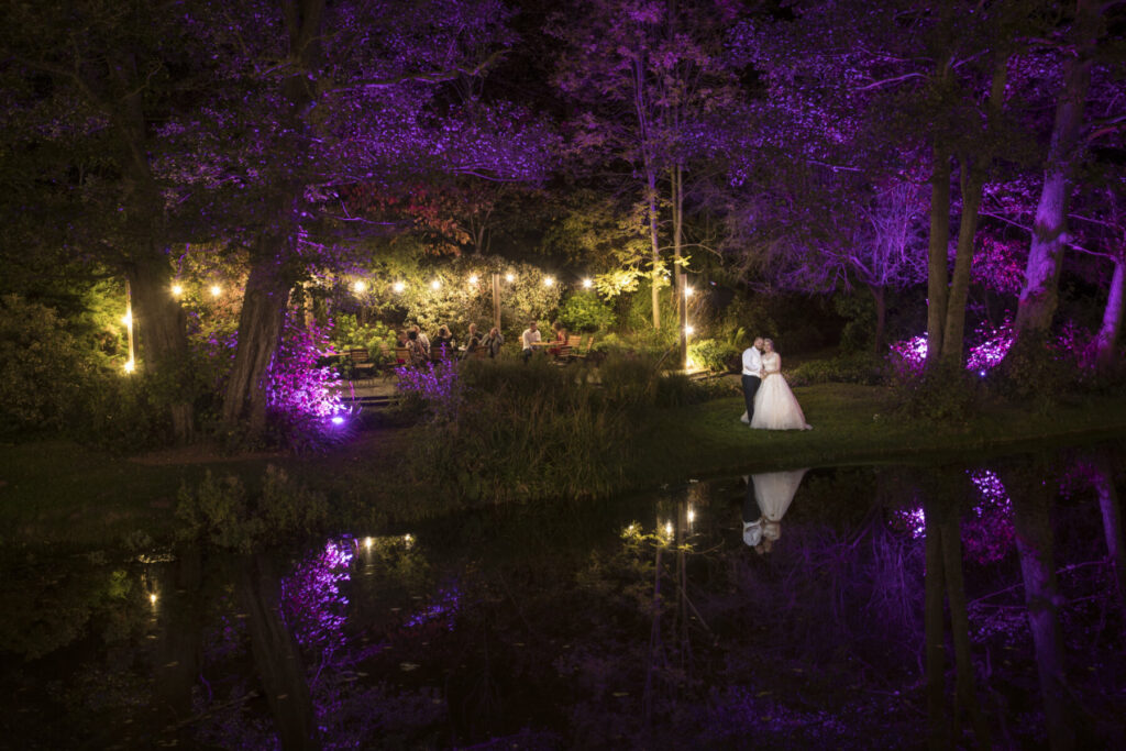 alt="Bride and groom night portrait beside the pool at The Mill Barns wedding venue"