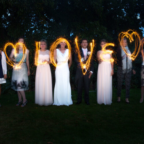 Julia & Andy - Wedding guests with sparklers creating the word Love in the evening light at Sherbourne Park Wedding Venue